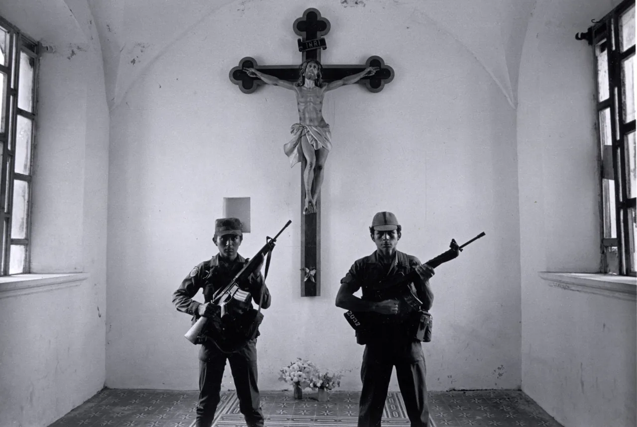 Black-and-white photograph of two armed soldiers standing symmetrically inside a church beneath a large crucifix.